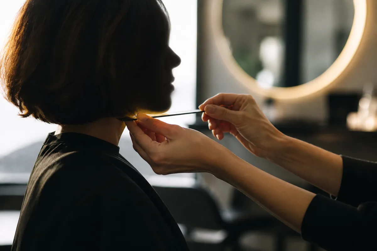 Coiffeuse mesurant la distance entre le lobe de l’oreille et le menton
